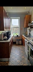 a kitchen with wooden cabinets and a large window at Double Room - Folkestone Harbour in Kent