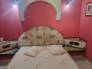 a bed in a room with a pink wall at Max Motel in Jaguariúna