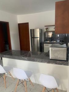 a kitchen with a counter with four white chairs at Comoda y hermosa casa MINDY in Tuxpan de Rodríguez Cano