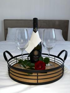 a tray with two wine glasses and a bottle on a bed at City Nest, Free Parking & City Center in Prijedor