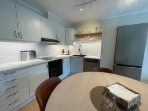 a kitchen with a wooden table and a kitchen with white cabinets at City Svolvær Apartment in Svolvær +7 photos