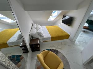 a room with two beds and a yellow chair at New apartman Summer in Kaštela