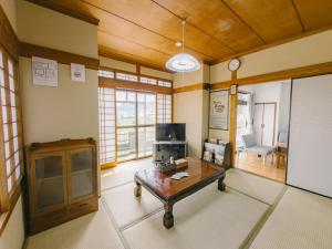 a living room with a coffee table and a tv at 温泉街近くの一棟貸し ひだまり in Kirishima