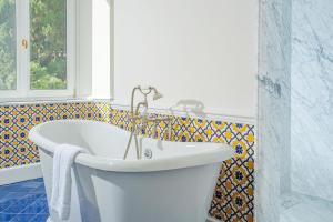 a white bath tub in a bathroom with a window at Villa Helios Capri - Small Luxury Hotels of the World in Capri