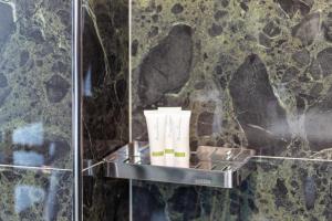 a shelf with three rolls of toiletries in a bathroom at D&D HOTEL Ksamil in Ksamil