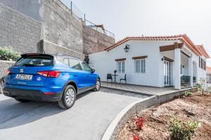 a blue car parked in front of a white house at Sweet Home Madeira in Camacha