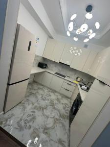 a kitchen with white cabinets and a marble floor at Бахт in Bishkek