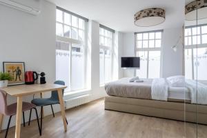 a bedroom with a bed and a desk and windows at Stadslogement Kingsize in Sneek