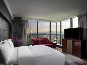 a bedroom with a large white bed and a tv at Sofitel Kunming in Kunming