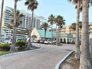 a parking lot with palm trees and a building at Sunkissed-Modern Oceanfront Condo Daytona Beach in Daytona Beach