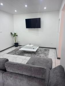 a living room with a couch and a tv on a wall at Résidence Atoumo in Rivière-Pilote +2 photos