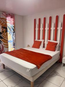 a bedroom with a large bed with red and white pillows at Résidence Atoumo in Rivière-Pilote