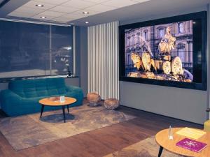 a living room with a blue couch and two tables at Mercure Madrid Centro in Madrid