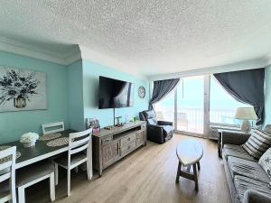 a living room with a couch and a table with a dining room at Sunkissed-Modern Oceanfront Condo Daytona Beach in Daytona Beach