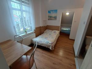 a small room with a bed and a table and a window at u Oli Dawid Spaczyński in Mrzeżyno
