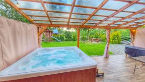 a hot tub in a backyard with a pergola at Urocza Kryjówka ze SPA in Lesko
