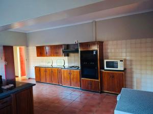 a large kitchen with wooden cabinets and a microwave at Oolele BnB Newcastle in Newcastle