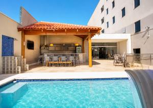 a swimming pool with a pergola next to a building at MAPER MARDAN in Parauapebas