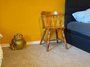 a wooden chair in a bedroom with a frog next to a bed at Modern Stay Apartments in Kassel
