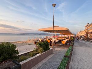 a sidewalk with tables and umbrellas on a beach at Coastal Heaven in Neoi Epivates