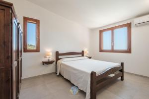 a bedroom with a bed and two windows at Villa Panorama Private Pool Costa Rei in Monte Nai +49 photos