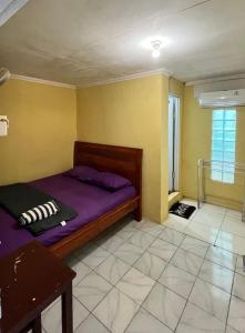 a bedroom with a purple bed and yellow walls at Motel Gemilang in Karimunjawa