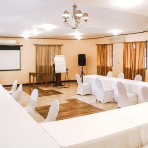 a conference room with white chairs and a screen at Drift Inn Cayo in Santa Elena