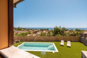 a swimming pool in a yard with a view of the ocean at Villa Panorama Private Pool Costa Rei in Monte Nai