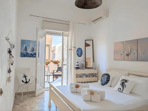 a white bedroom with a bed and a balcony at Libeccio House in Avola