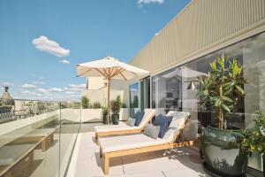 a balcony with two chairs and an umbrella at Nobu Hotel Madrid in Madrid