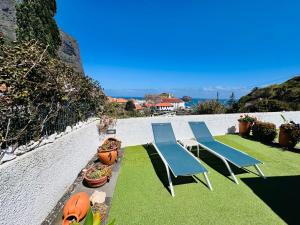 two blue chairs and a table and some plants at Estúdio Villa Matilde e Joaquim in Porto da Cruz