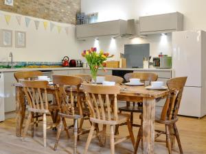 a kitchen with a wooden table with chairs and a refrigerator at 'Ow Do - Uk11446 in Skipsea