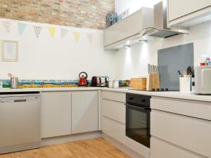 a kitchen with white cabinets and a stove at 'Ow Do - Uk11446 in Skipsea +18 photos