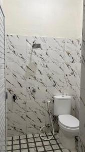 a white bathroom with a toilet and a shower at Kos Pramuka in Sunggal