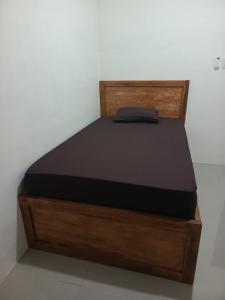 a bed with a wooden bed frame in a room at Kos Pramuka in Sunggal