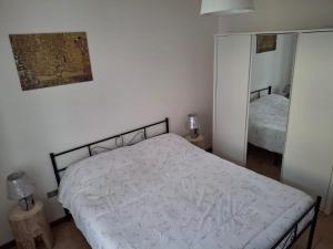 a bedroom with a white bed and a mirror at Appartamento Felis in Molina di Ledro