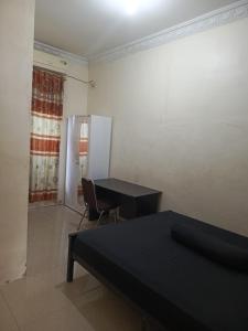 a room with a desk and a table and a chair at Kos Pramuka in Sunggal