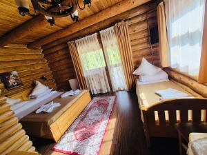 a bedroom with two beds in a log cabin at Pensiunea Moeciu Casa Wiarusti in Moieciu de Sus