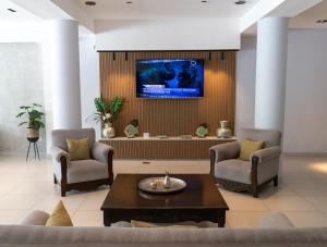 a living room with two chairs and a tv on a wall at Hotel Termal Emperatriz Termas de Río Hondo in Termas de Río Hondo