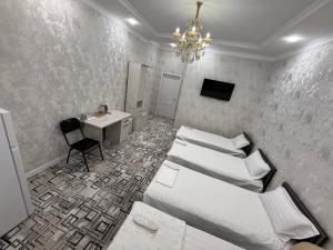 a room with three beds and a desk and a chandelier at Golden Emir Residence in Bukhara