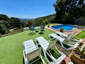 a group of lawn chairs sitting next to a pool at Alojamientos COBALTO CASA PARAÍSO in Sant Cebrià de Vallalta