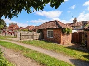 a brick house with a fence in a yard at The Cooks Cottage in Malton
