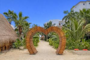 an archway on a beach with palm trees at Arenika Beachfront Villa & Rooms in Puerto Morelos
