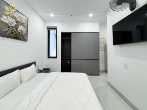 a bedroom with a large white bed and a tv at Hotel Gold Beach in Phương Phi