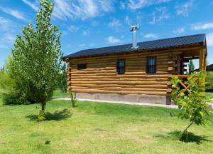 a log cabin in a field with a tree at Finca La Vilina - Cabaña Aurora in San Rafael