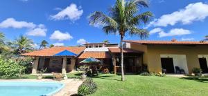 a house with a palm tree and a swimming pool at Pouso do Kite Pousada Flecheiras in Flecheiras