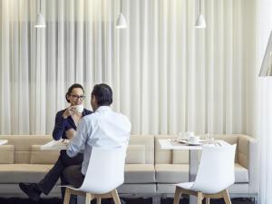 a man and a woman sitting on chairs in a room at Mercure Hotel Golf Cap d'Agde in Cap d'Agde