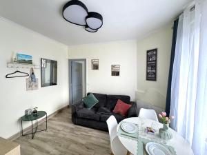 a living room with a black couch and a table at T2 cosy & calme - Gare à 1 min accès direct Paris & CDG in Aulnay-sous-Bois