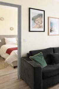 a living room with a couch and a bed and a mirror at T2 cosy & calme - Gare à 1 min accès direct Paris & CDG in Aulnay-sous-Bois