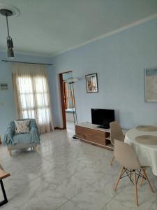 a living room with a tv and a couch and a table at Apostolis Seaside Living in Olympiada